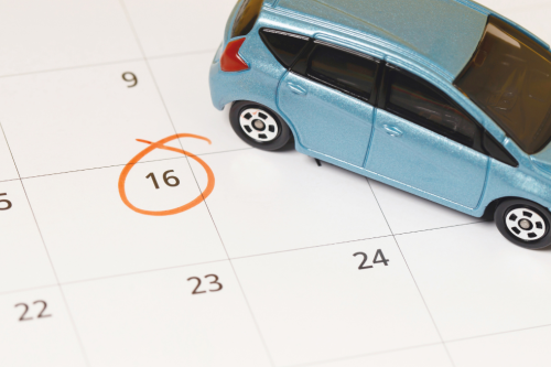 Carro em miniatura sobre um calendário com uma data assinalada a laranja